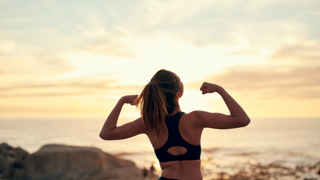 Image for the blog post - 5 habits to boost your mental and physical health. A woman showing muscles. 